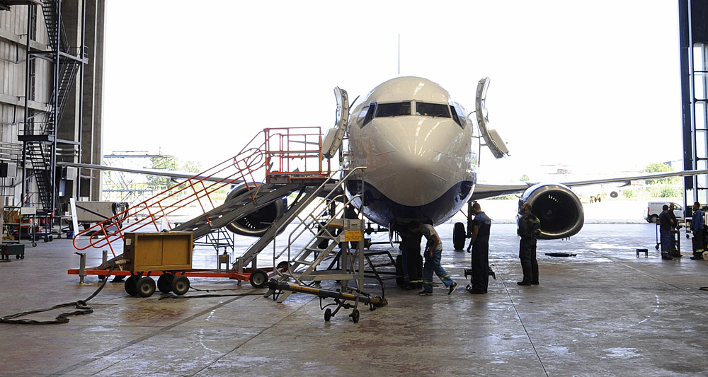airplane parked in a hangar being worked on by technicians